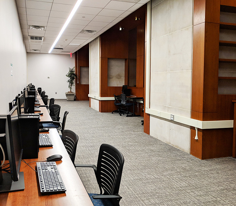 Long room with desks and chairs along the table. Students study at the tables.